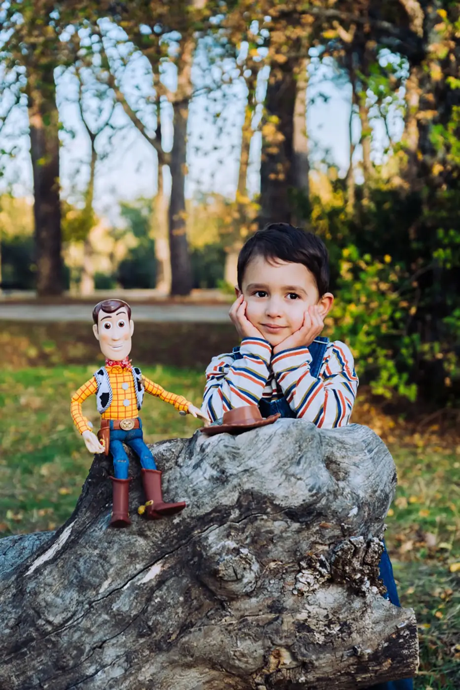 Boy leaning on a rock next to his toy cowboy